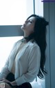 A woman sitting on a bed next to a window.