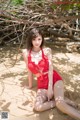 A woman in a red bikini sitting on the sand.