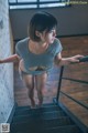 A woman in a gray shirt is walking up some stairs.