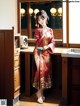 A woman in a red kimono standing in a kitchen.