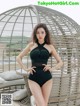 A woman in a black one piece swimsuit posing for a picture.