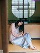 A woman sitting on the floor in front of a window.