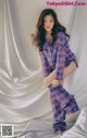 A woman in a plaid pajamas sitting on a bed.