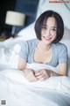 A woman laying on a bed smiling at the camera.