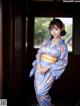 A woman in a blue kimono posing for a picture.