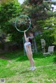 A woman in a white bathing suit holding a hula hoop.