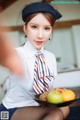 A woman in a white shirt and tie holding a plate of fruit.