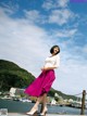 A woman in a white shirt and a pink skirt posing for a picture.