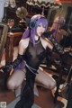 A woman with purple hair is posing in a black lingerie.