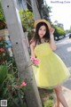 A woman in a yellow dress and straw hat posing for a picture.