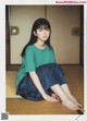 A young woman sitting on the floor wearing a green shirt.