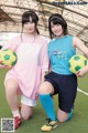 Two young women posing for a picture with soccer balls.