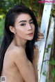 A woman with long black hair leaning against a white fence.