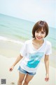 A woman standing on a beach next to the ocean.