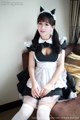 A woman dressed as a maid sitting on a couch.