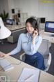 A woman sitting at a desk talking on a cell phone.