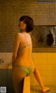 A woman in a green lingerie standing in a bathroom.