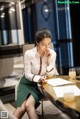 A woman sitting at a table writing on a piece of paper.