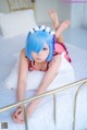 A woman with blue hair laying on a bed.