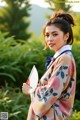 A woman in a kimono holding a fan in her hand.