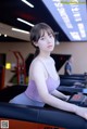 A woman sitting on a treadmill in a gym.