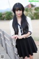 A woman with long black hair standing next to a wooden fence.