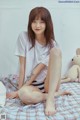 A woman sitting on a bed with a teddy bear.