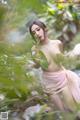 A woman in a pink dress is posing in the woods.