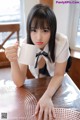 A woman sitting at a table holding a cup of coffee.