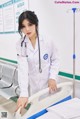 A woman in a white lab coat standing next to a hospital bed.