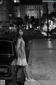 A woman standing next to a car on a city street.