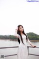 A woman in a white dress standing on a bridge.