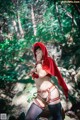 A woman dressed as a red riding hood in the woods.