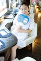 A woman sitting at a table holding a fan.