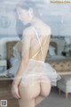 A woman in a white lingerie standing in front of a window.