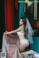 A woman in a white lingerie sitting on a chair.