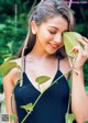 A woman in a black dress holding a green leaf.