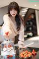 A woman standing in front of a table with a cake and strawberries.