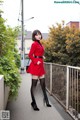 A woman in a red coat and black tights posing for a picture.