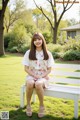 A woman sitting on a white bench in a park.